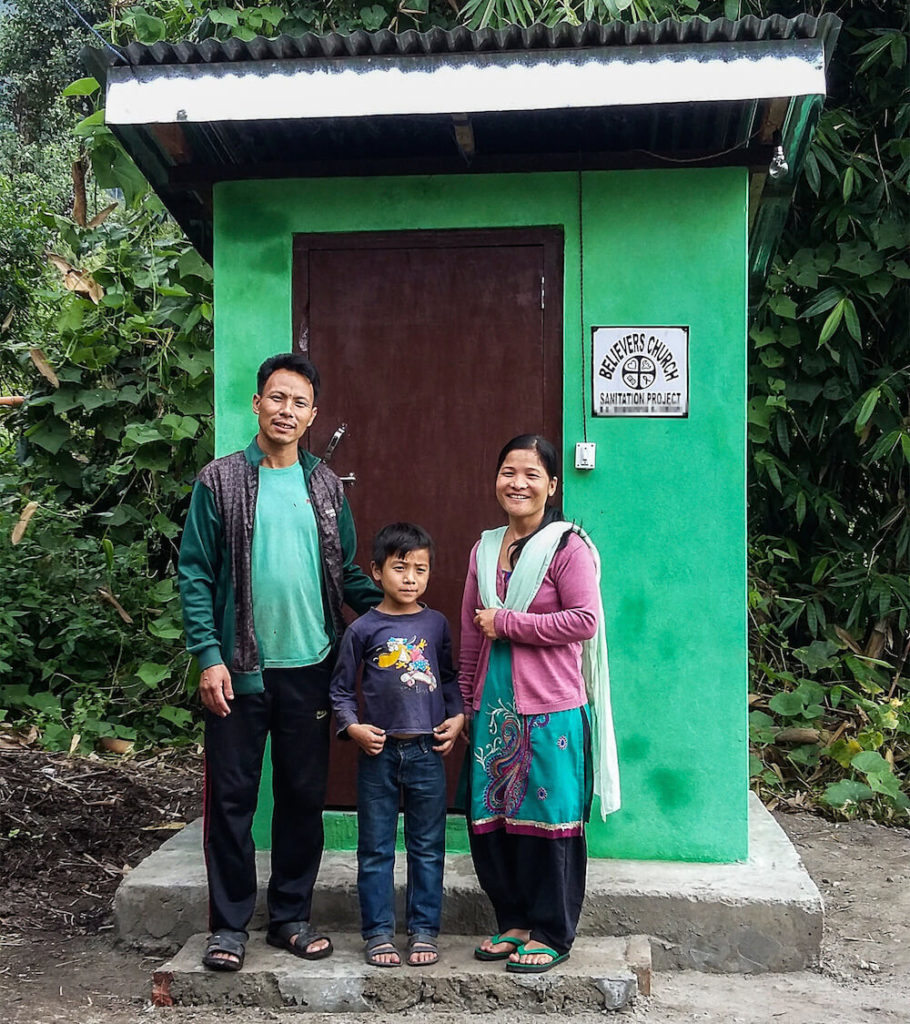 A Asian family in front of a GFA-provided local sanitation facility: outdoor toilets