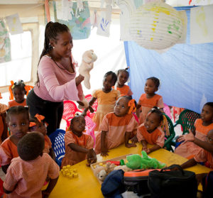 An instructor plays with kindergarten children at an Internally Displaced Persons camp in Haiti. 