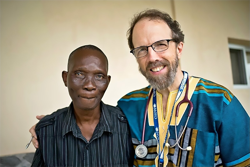 A patient from ELWA (Eternal Love Winning Africa) Hospital in Liberia, West Africa with Dr. Rick Sacra, a U.S. Medical Missionary. Dr. Sacra has been doing medical missionary work in Liberia for SIM, an international Christian missionary organization for 25 years, and has been recognized with the 2018 AMH Gerson L'Chaim (