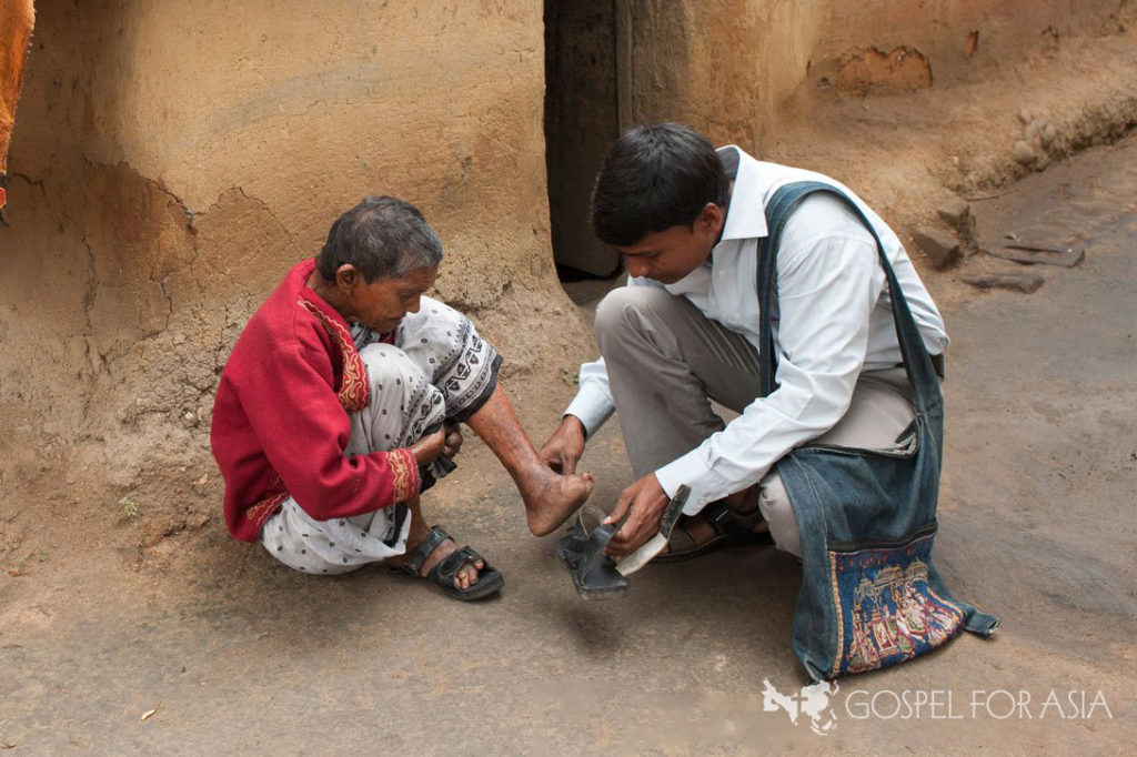 Gospel for Asia-supported pastor helps a leprosy patient.