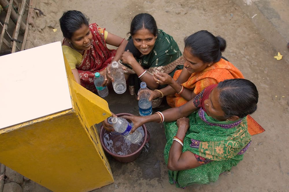Women filling up water bottles using BioSand Water Filter