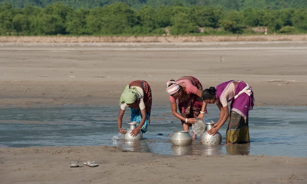 Women drawing water from a dirty and dried up river